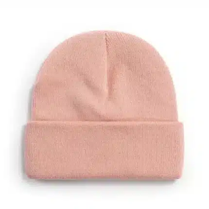 Pastel pink knitted beanie hat with folded cuff on white background.