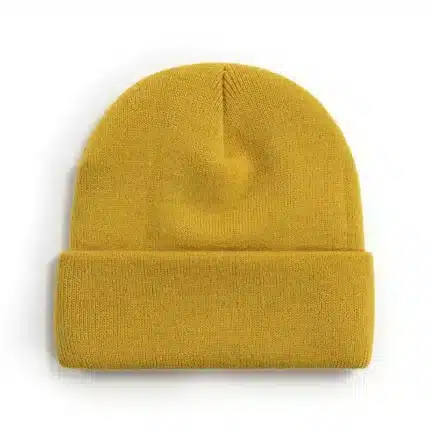 Mustard yellow knitted beanie hat on white background.