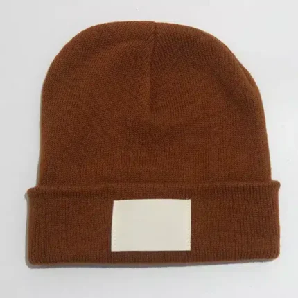 Brown knit beanie with fold-over cuff and patch on light surface.